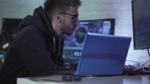 Programador concentrado en anteojos que trabaja con varios ordenadores y portátiles en interiores.
Retrato