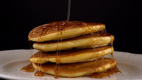 American pancakes with maple syrup on a black background.