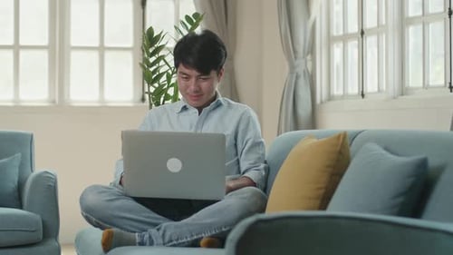 Man working on laptop computer on sofa