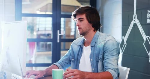 Mann trinkt Kaffee, während er am Computer arbeitet