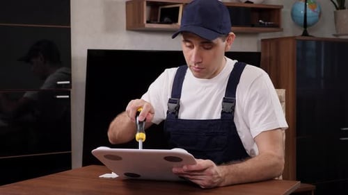 Man Repairing Electronic Device with Screwdriver at Table