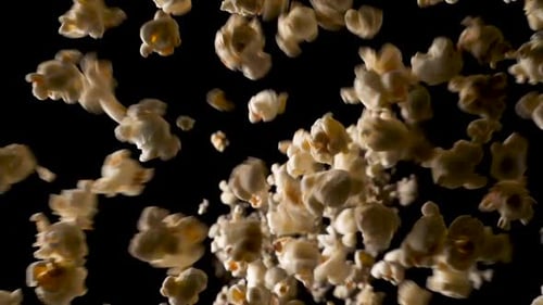 A large amount of popcorn falls in slow motion on the camera until the whole frame is covered with i
