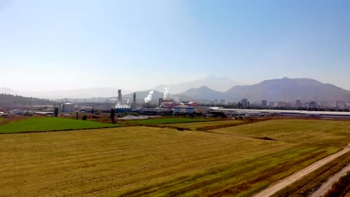 Una fábrica de azúcar con humo subiendo en los campos