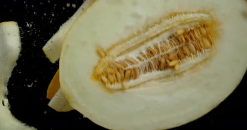 Des tranches de melon frais tombent sous l'eau.