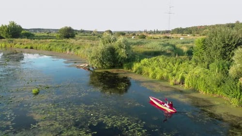 Woman is kayaking on river at countryside at sunset. Tourist is floating in canoe in summer.