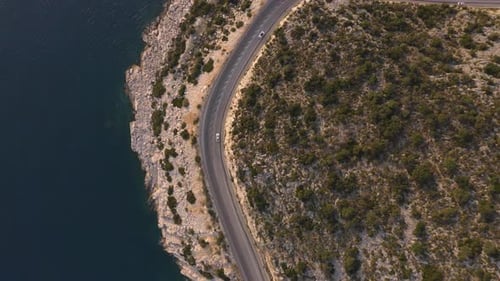 Aerial View From Drone of Cars Going Through Mountain Road Above Rocky Coast