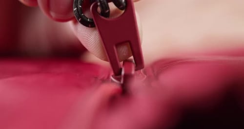 Hand Zipping Up Red Clothes Closeup