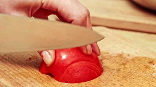 Hand Slicing a Tomato on a Wood Board