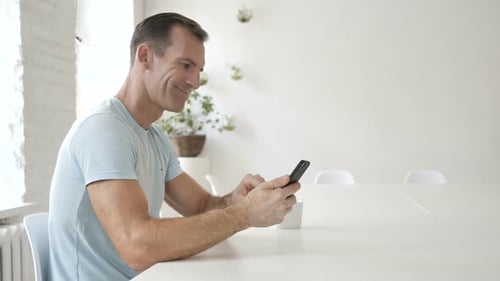Man Using Smartphone at Table Indoors