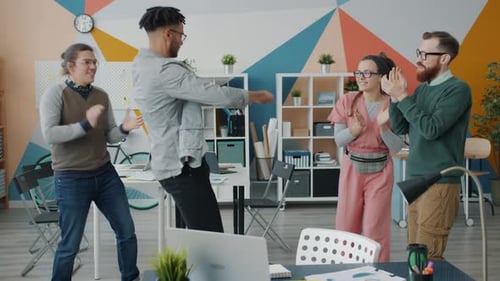 Portrait of Playful Afro-American Man Dancing in Office Having Fun with Colleagues