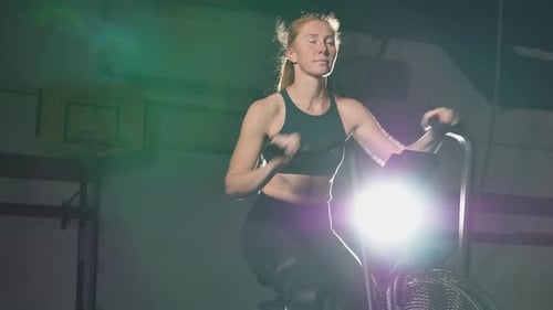 Woman Exercising on Stationary Bike in Gym