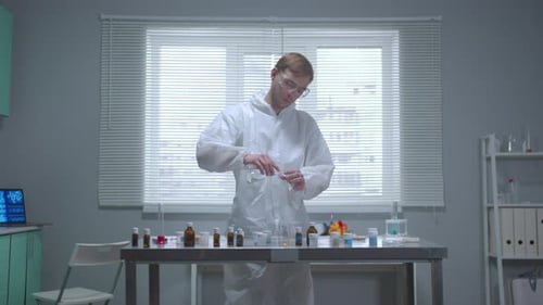 Un homme en tenue de travail protectrice verse du liquide dans un tube au laboratoire
