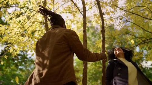 Family Enjoy Autumn Park Dancing Under Falling Leaves in Warm Golden Sunlight