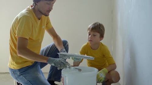Man and Child Putting Plaster on a Wall