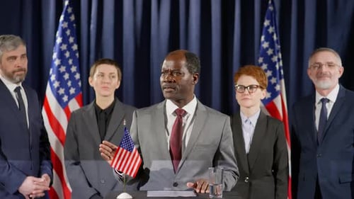 Politician Gives Speech at Podium Surrounded by Supporters