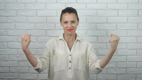 Woman Poses with Raised Fists in Front of Wall