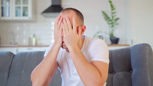 Distressed Man Sitting on Sofa at Home