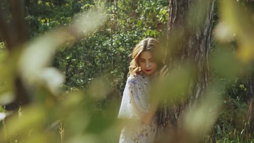 Portrait of Beautiful Young Caucasian Woman with Red Lips Posing in the Forest Near Tree Bark
