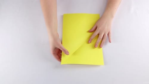 Hands Making Origami with Bright Yellow Paper