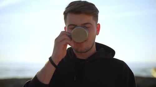 Man Drinks Coffee at Beach at Sunrise