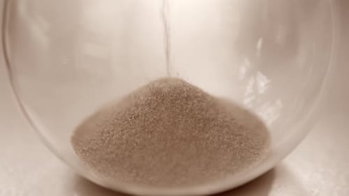 Hourglass sand falling in slow motion close up