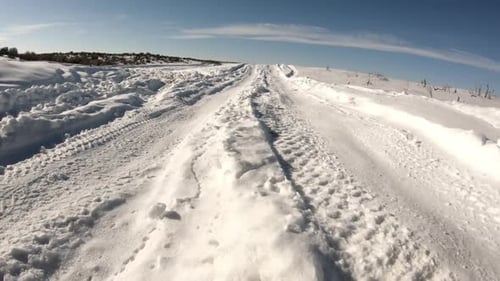 Low view driving through snow on winding road