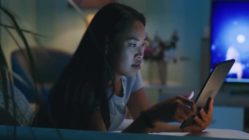Woman Using Tablet in Dark Living Room
