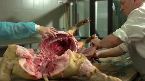 Butcher Cutting Pork Carcass at the Meat Manufacturing