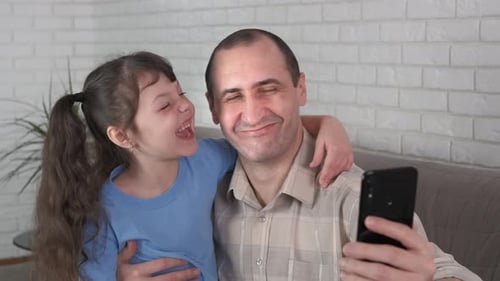 Smiling Father and Child Taking Selfie Together Indoors