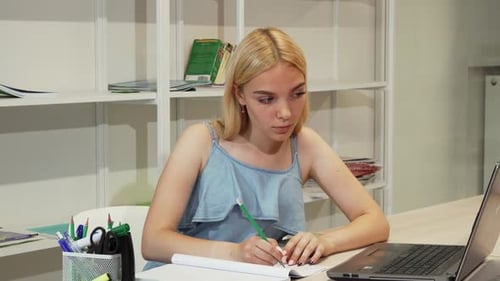 Young Adult Studying with Laptop and Notebook
