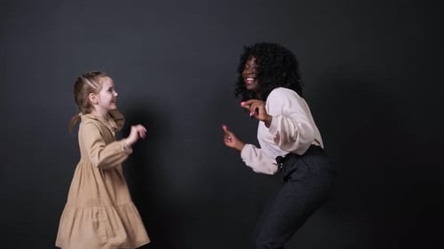 Active Black Lady and Smiling Blonde Schoolgirl Dance