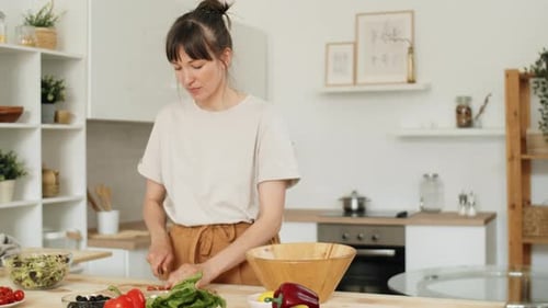 Woman Prepares Healthy Salad in Bright Kitchen