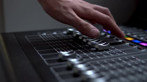 Man Works on a Professional Electronic Audio Mixer. A Control Panel for Tuning Sound Channels