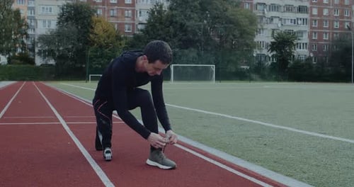 Young Adult Ties Shoelaces on Outdoor Track