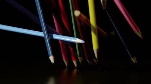 Colorful Wood Pencils Falling onto Black Surface