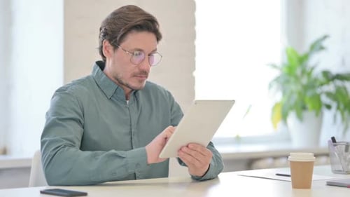 Attractive Middle Aged Man using Tablet in Office