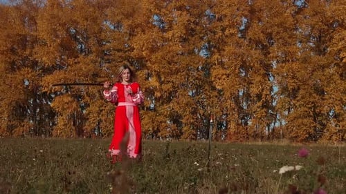 Militant Concept on an Autumn Field - Feisty Blonde Woman in Red Dress Training Her Swordplay