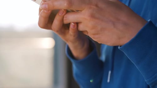 Female Hands Using Smartphone Against the Setting Sun.