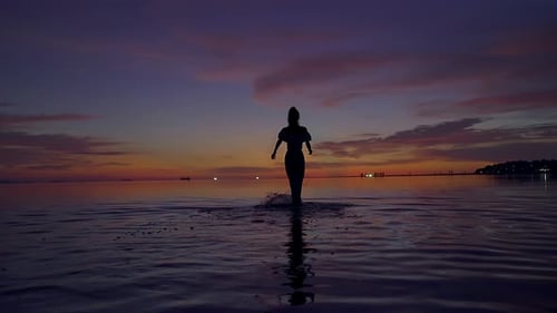 Young Woman Silhouette Walking in the Sea at Beautiful Sunset Thailand