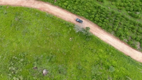 Aerial View of Car Driving Throuh a Small Dirt Road in the Middle of Green Tropical Valley.