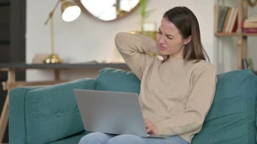 Woman Massaging Neck with Pain While Using Laptop