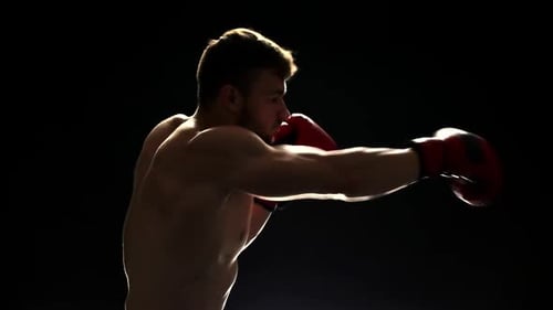 Man Boxing in Dark Studio with Red Gloves