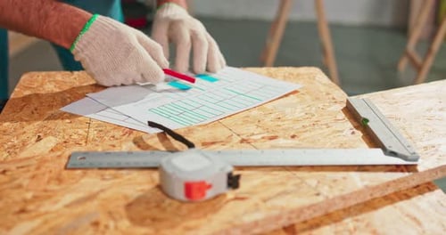 Closeup of a Hardworking Professional Carpenter Holding a Angular Ruler and Pencil While Measuring a