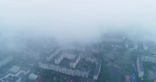 The camera flies over the city, a view through the clouds at city houses