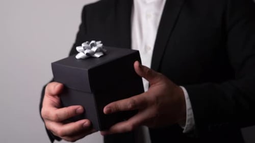 Man in Suit Presenting a Gift Box