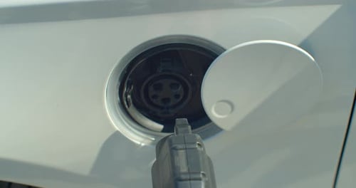 Close Up Of Hand Attaching Power Cable To Environmentally Friendly Zero Emission Electric Car.