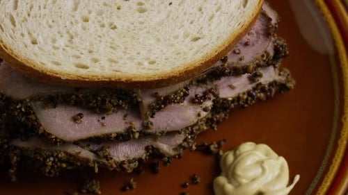 Chupito rotativo de delicioso sándwich de pastrami de primera calidad junto a una cucharada de mostaza de Dijon