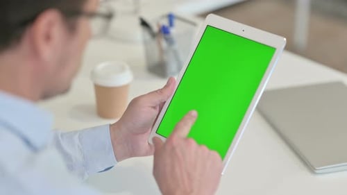 Man Tapping Tablet with Green Screen at Work