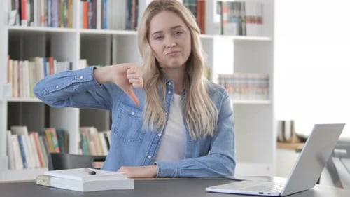 Young Woman Giving Thumbs Down Gesture at Desk