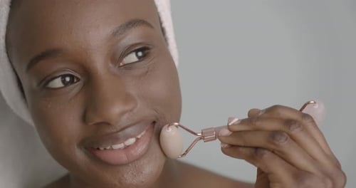 Elegant Woman Uses Facial Roller for Skincare Routine
